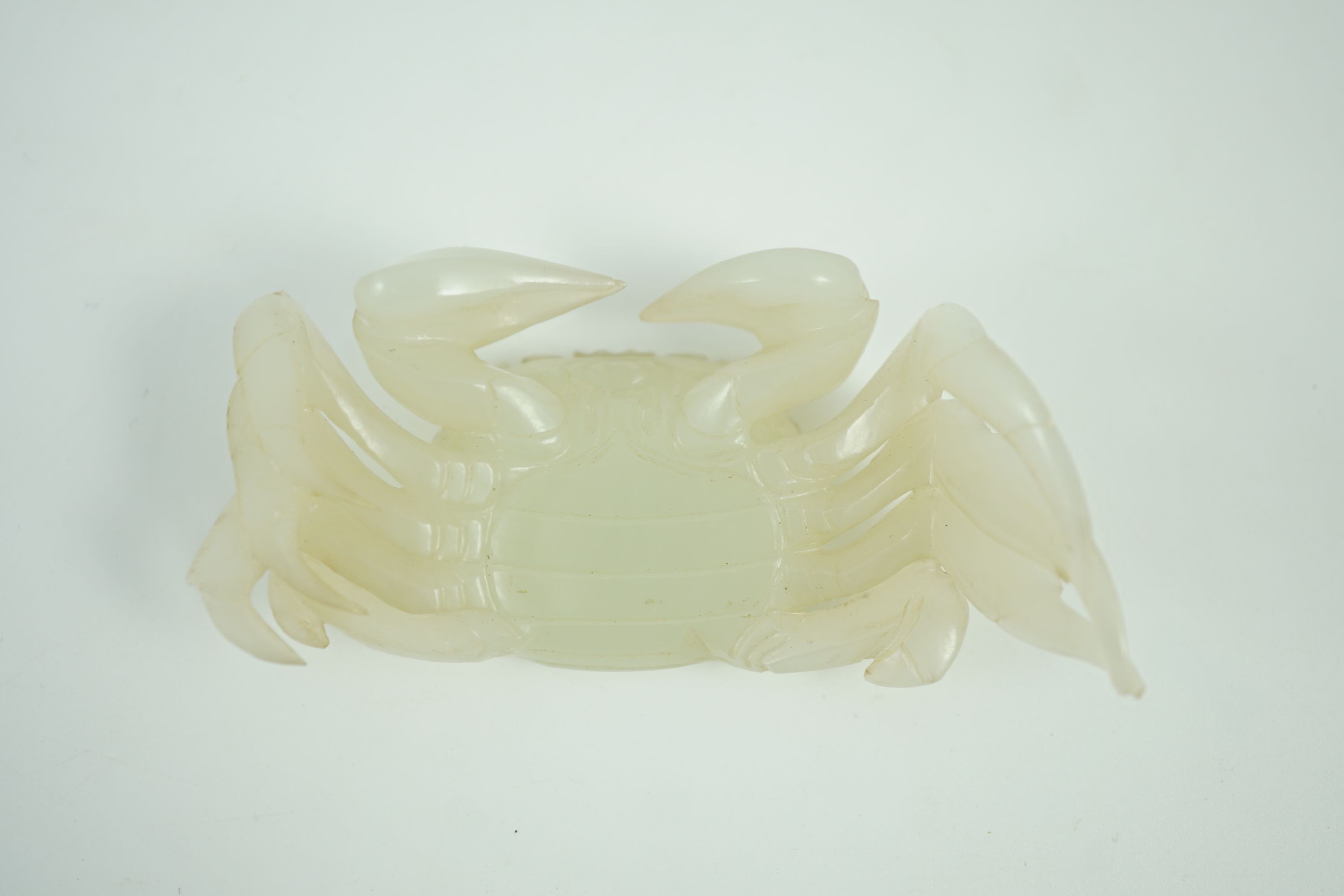 A Chinese pale celadon jade model of a crab, 20th century, 8.4 cm wide, wood stand